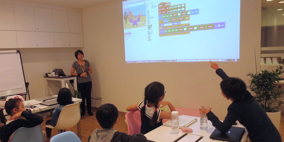LCCL students watching a Scratch project on the projector as the teacher explains the code